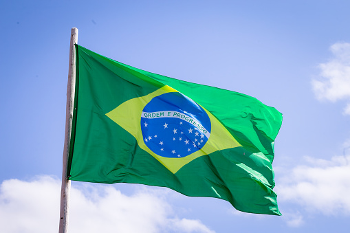 Tela textil de la bandera nacional de Brasil ondeando en la parte superior, cielo azul brasil, concepto de patriotismo. photo