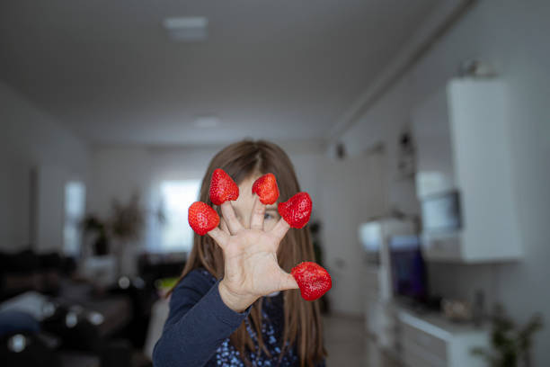 A little girl eating strawberries and putting them on fingers