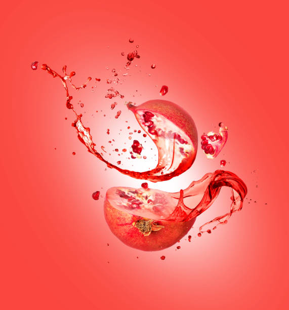 Juice splashes out from chopped pomegranate on a red background