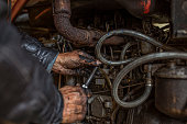 An older American truck driver repairing a machine