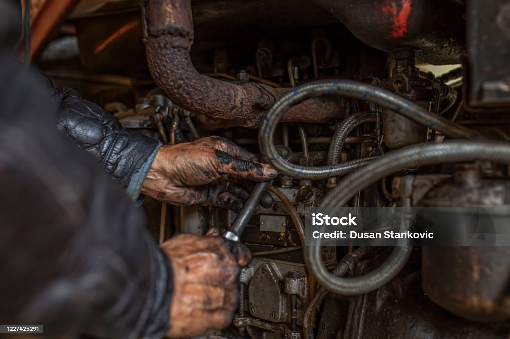 An older American truck driver repairing a machine American driver repairing and old truck Tractor Stock Photo