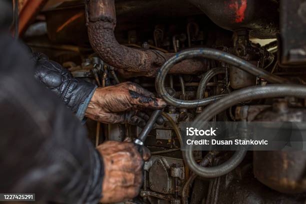 An Older American Truck Driver Repairing A Machine Stock Photo - Download Image Now - Tractor, Repairing, Agricultural Machinery