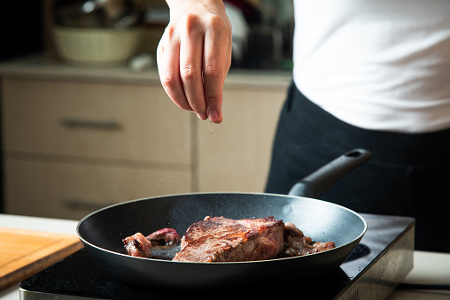 Woman frying Wagyu Japanese beef steak on the pan. Home food preparation