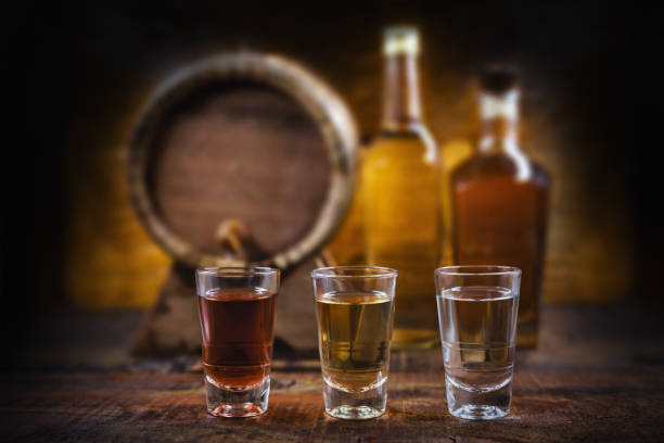 bouteille de cachaça avec le reste et le verre. couleur dorée brésilienne de cachaça, avec la texture de bois en haute résolution - liqueur photos et images de collection