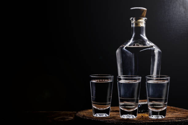 aguardiente ou aguardente bebida alcoólica tradicional espanhola e brasileira, bebida forte, conhaque de uva, rum, gim, tequila prateada, pinga, cachaça brasileira, vodca russa, em copos em uma velha mesa de madeira rústica, lugar para texto. bebida tra - tequila bebida branca - fotografias e filmes do acervo