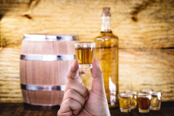 hand holding glass of alcoholic drinks, cachaça, pinga, rum and cognac. selection of strong and hard alcoholic drinks, glasses. vodka, cognac, whiskey, grappa, liqueur, vermouth, rum. space for text. - food and drink industry imagens e fotografias de stock