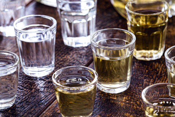 酒飲料のグラス、 ボトルを背景に、素朴な設定。ブラジルの金型カシャサ、ピンガと呼ばれる。 - whisky alcohol pouring glass ストックフォトと画像
