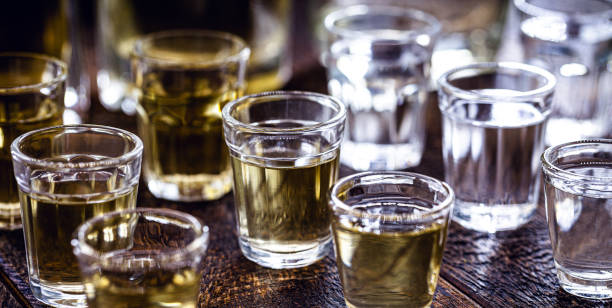酒飲料のグラス、 ボトルを背景に、素朴な設定。ブラジルの金型カシャサ、ピンガと呼ばれる。 - whisky alcohol pouring glass ストックフォトと画像