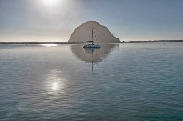 istock Morrow Bay Rock with Boat in Bay reflections and Sun 1227432330