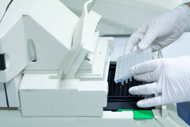 Researcher or scientific introducing a plate in quantitative PCR machine in a biotechnology laboratory Researcher or scientific introducing a 96 wells plate in quantitative PCR machine/ Thermocycler for DNA or RNA quantification in a biotechnology laboratory quantitative research stock pictures, royalty-free photos & images