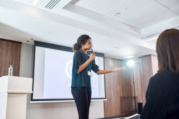 istock Igniting Team Spirit. Female speaker with microphone giving a powerful talk on corporate business meeting 1227437875