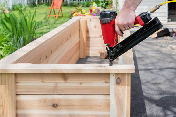 Closeup of a man using a power nail gun on a woodworking project with sawdust flying Closeup of a man using a pneumatic nail gun to finish the trim on cedar garden planters with sawdust flying flowerbed stock pictures, royalty-free photos & images