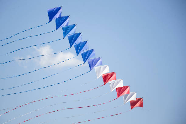 A multi tiered red white and blue kite flies through the air stock photo