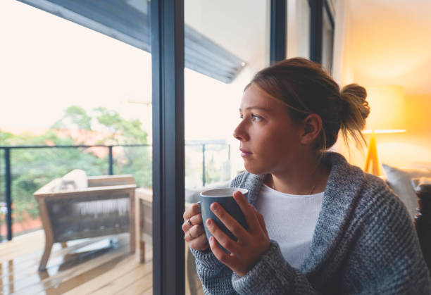 istock Woman looking through the window drinking tea or coffee. 1227453285