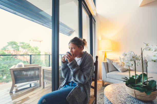 istock Woman looking through the window drinking tea or coffee. 1227453287