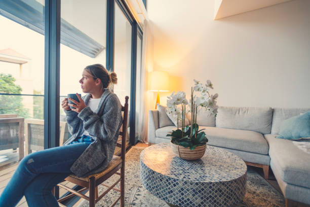 istock Woman looking through the window drinking tea or coffee. 1227453288