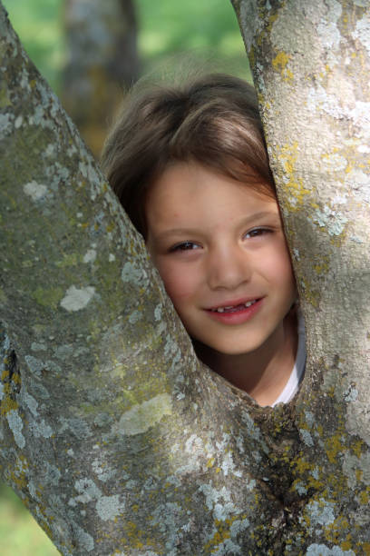 istock Young caucasian female peeking out from tree 1227460471