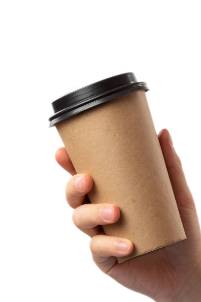 istock Breakfast and coffee theme: man's hand holding empty paper coffee cup with a brown plastic cap isolated on a white background in the studio, advertising coffee 1227462960