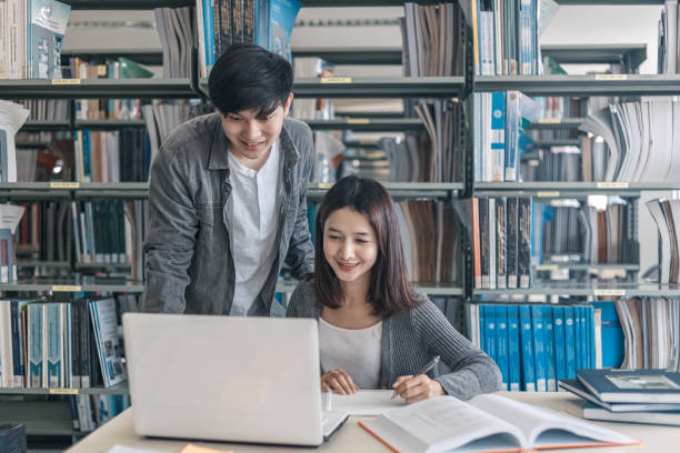istock High school or college students studying and reading together in library. Student use laptop at library. 1227464421
