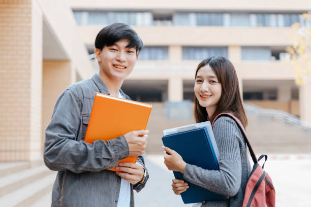 istock high school students hold book and laptop talking and laughing in a hallway between classes 1227465318