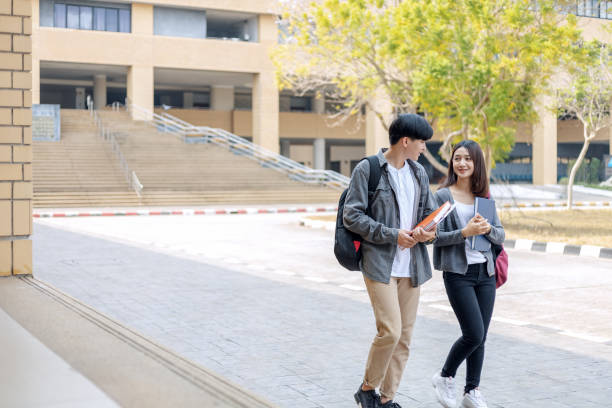 istock high school students hold book and laptop talking and laughing in a hallway between classes 1227465339