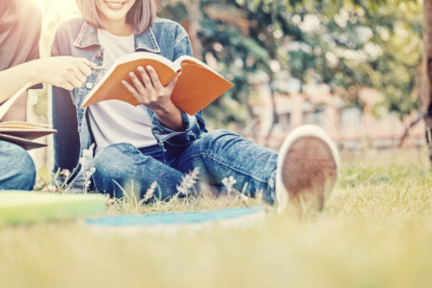 istock University students sitting and reading a book on the grass. 1227465401