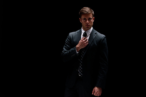 Front view of aged 20-29 years old with brown hair caucasian male businessman in front of black background wearing businesswear who is in concentration