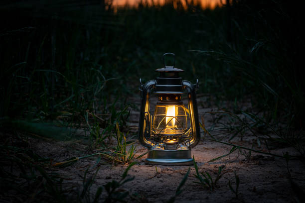 burning lantern stands in a cornfield at dusk