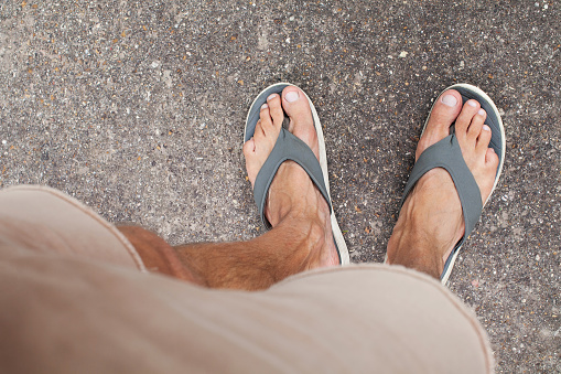 Top view on strong male legs and feet in flip flops. Healthy nails and skin. Concept of health and healthy lifestyle