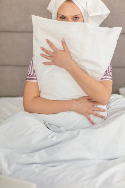 istock Young beautiful girl hugging pillow while sitting in the bed 1227480758
