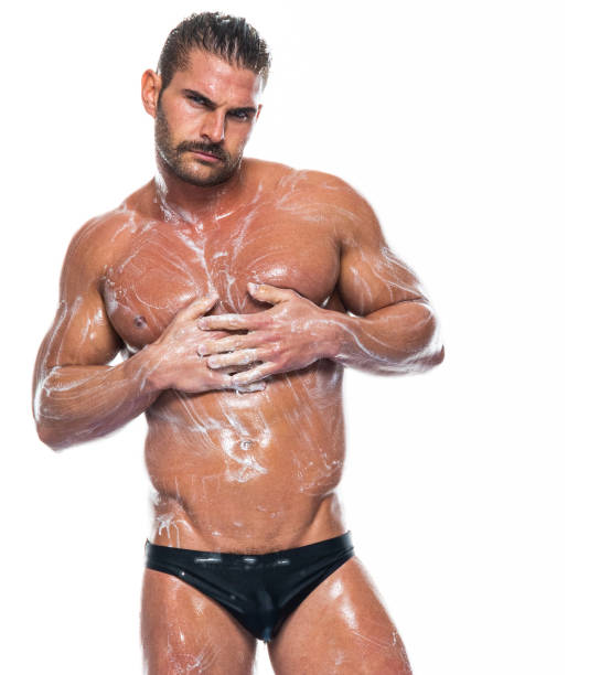 Caucasian male standing in front of white background wearing racing briefs Waist up of aged 30-39 years old with short hair caucasian male standing in front of white background wearing racing briefs who is of muscular build who is cleaning shower men falling water soap sud stock pictures, royalty-free photos & images