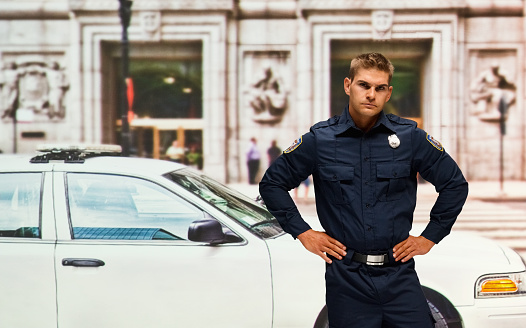 Professional Police Officer with Crossed Arms Looking at the Camera. Cop Maintains public order and safety, Enforcing the Law, Prevents and Investigates Criminal Activity. Cinematic Portrait