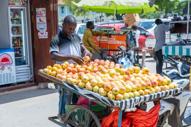 l'uomo africano vende mele fresche in un mercato locale di cibo di strada sull'isola di zanzibar, tanzania, africa orientale - africa agriculture zanzibar industry foto e immagini stock