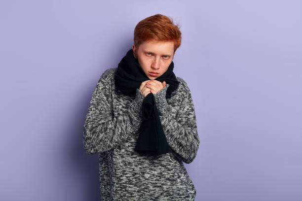 young red-haired man is freezing, feels cold, guy has cought a cold, flu - cought imagens e fotografias de stock