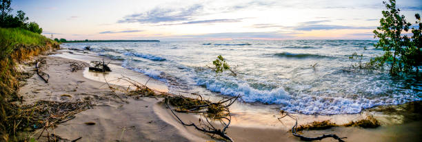 Waves hitting a Michigan beach on Lake Huron at sunset on a very windy day stock photo