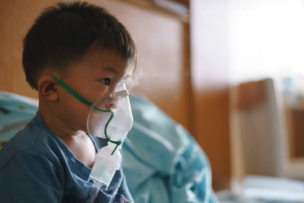 asiatischer junge mit inhalator mit medikamenten, um husten zu stoppen - asthmatic child asthma inhaler inhaling stock-fotos und bilder