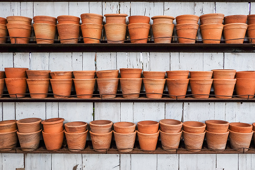 group of empty clay flower pots on a wooden shelf in a garden