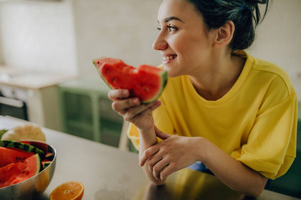istock Young woman eating watermelon in the kitchen 1227487497