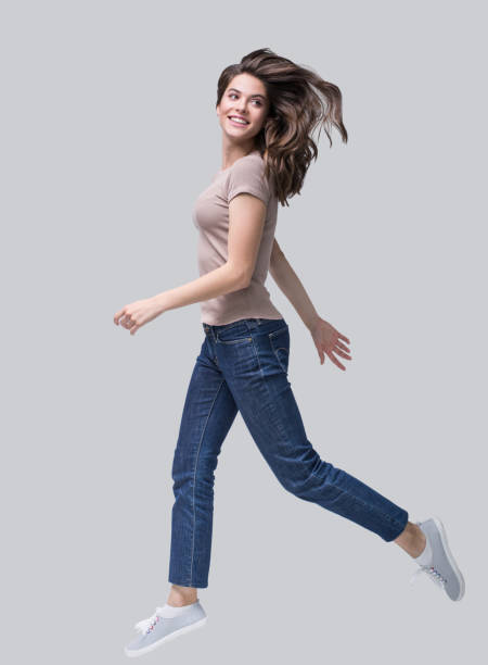 felice sorridente giovane donna che corre e si diverte - women action jumping running foto e immagini stock