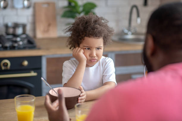 Cute little kid looking sad not wanting to eat stock photo