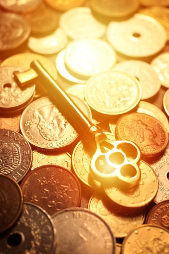 Golden Skeleton key on a pile of multinational coins.