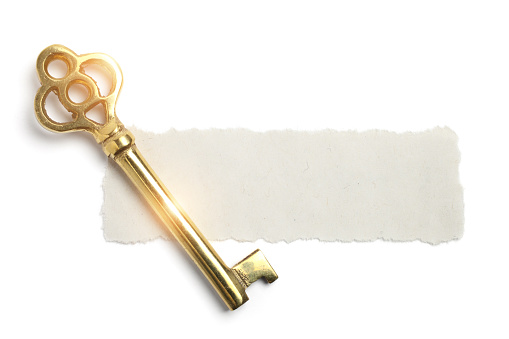 Piece of Blank Torn Scrap Paper with a Golden Skeleton Key on White Background.