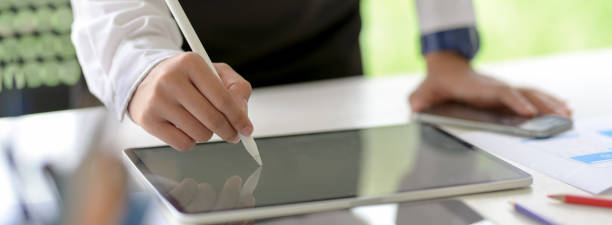 istock Businessman writing on mock-up tablet with stylus pen on white office desk 1227493571