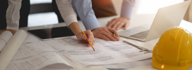 istock Two engineers working together with blueprint, laptop and tablet 1227493573