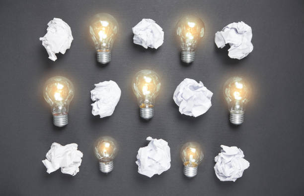 istock Light bulbs and crumpled papers on the black background. Idea 1227497347