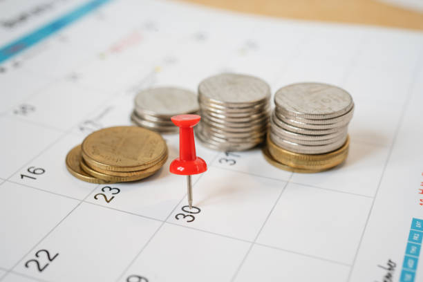 red pin marked on the end of month of calendar with blurred coins, business and finance background red pin marked on the end of month of calendar with blurred coins, business and finance background monthly event photos stock pictures, royalty-free photos & images