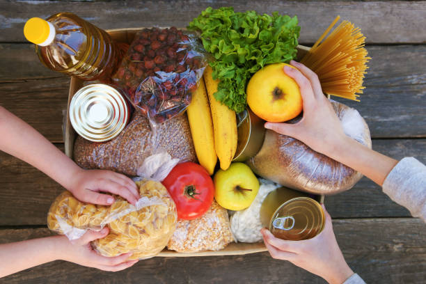 caja de donación con alimentos sobre fondo de madera viejo. - comida básica fotografías e imágenes de stock