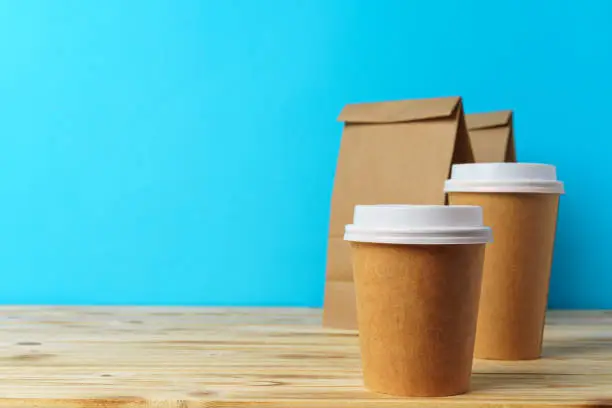 Photo of Paper bags with take away food and coffee cups containers