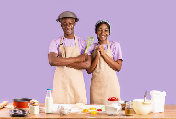 istock Joyful black couple with faces covered in flour baking together on violet background 1227502611