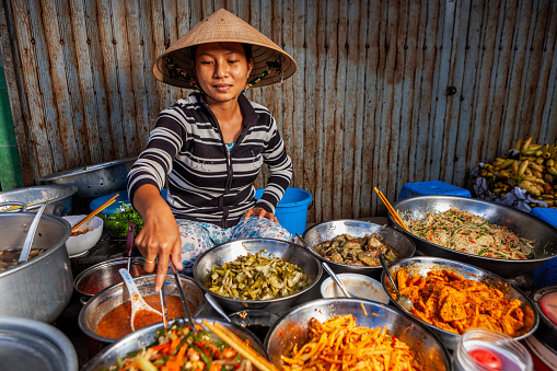 Vietnamese woman selling home made food at her food stand on the local market, Central Vietnam.